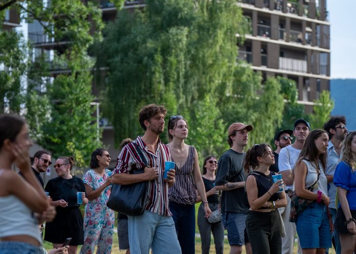 Menschen stehen zusammen und hören dem Parkkonzert zu.